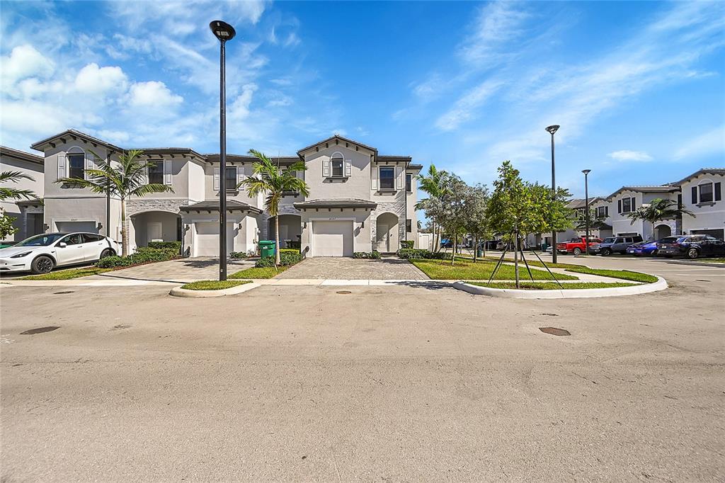 A row of two-story townhouses with paved driveways and palm trees under a blue sky — 20357 NW 4TH PATH, MIAMI, FL