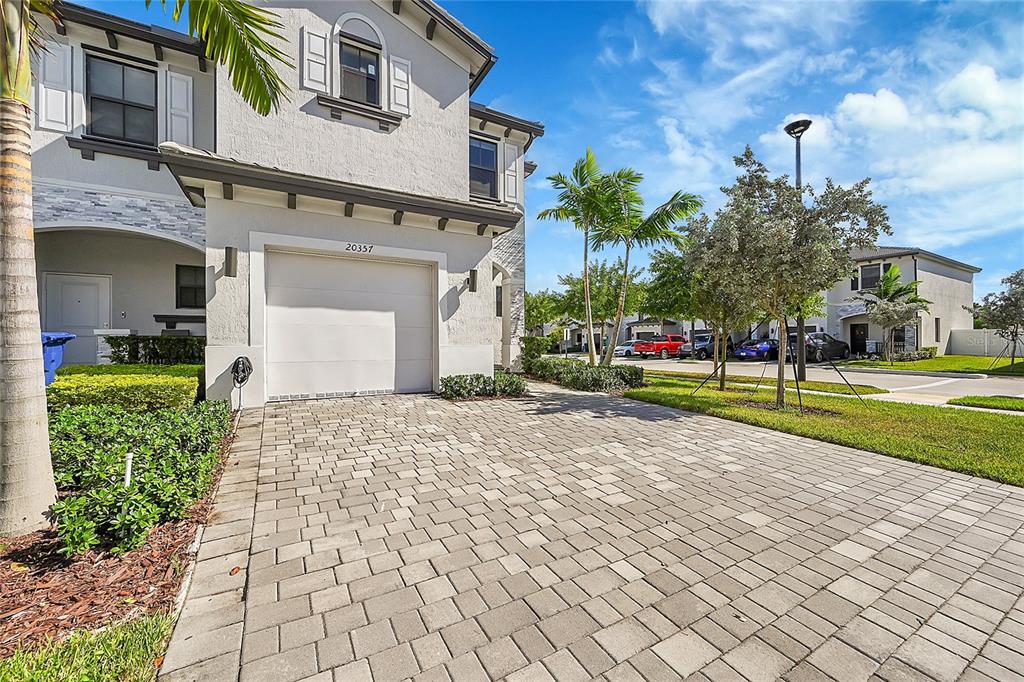 A two-story house exterior features a paved driveway, a single-car garage, and palm trees — 20357 NW 4TH PATH, MIAMI, FL