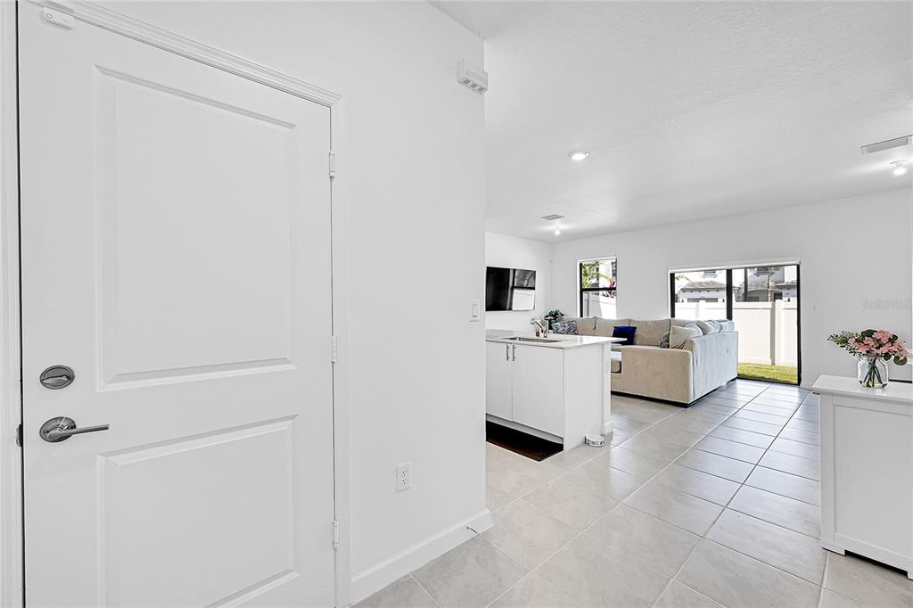 A white door opens into a bright, open-concept living area with tile floors and kitchen — 20357 NW 4TH PATH, MIAMI, FL