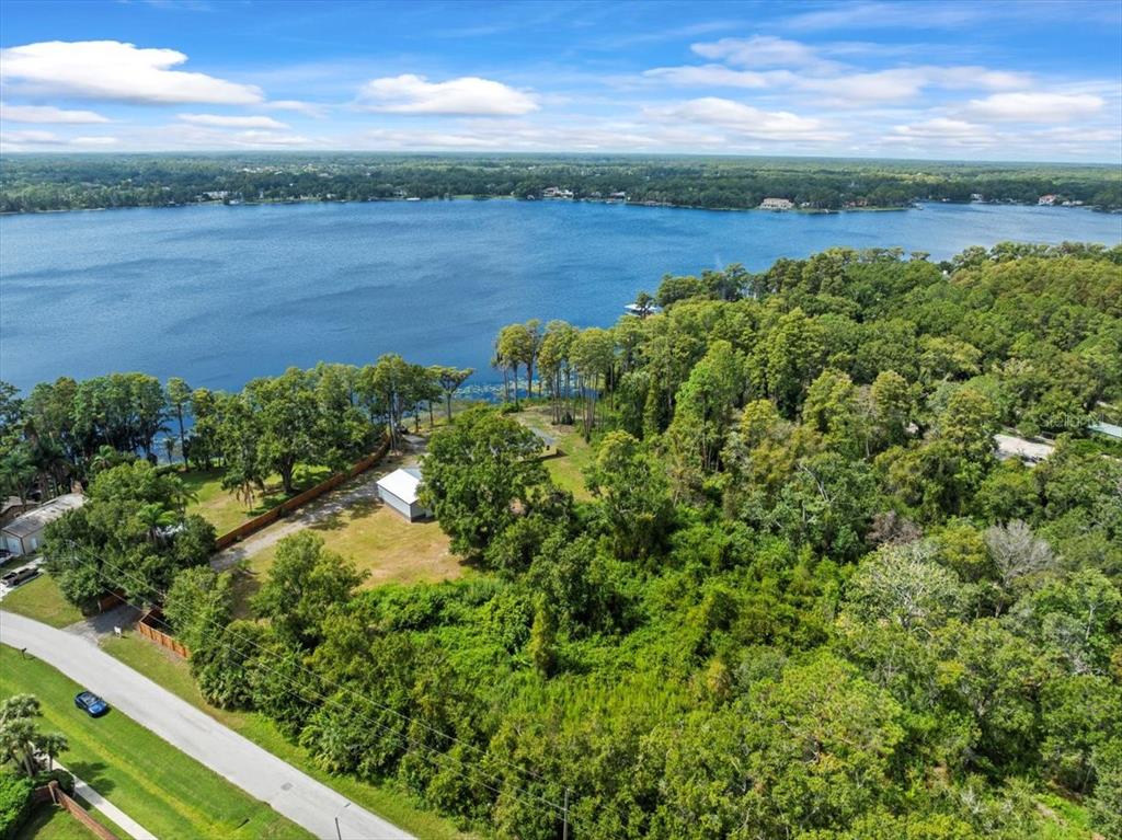 An aerial view shows a wooded lot with a small building near a large lake — 17924 SIMMS ROAD, ODESSA, FL