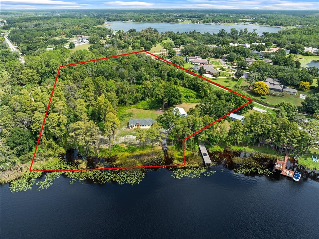 An aerial view shows a wooded waterfront property outlined in red next to a lake — 17924 SIMMS ROAD, ODESSA, FL