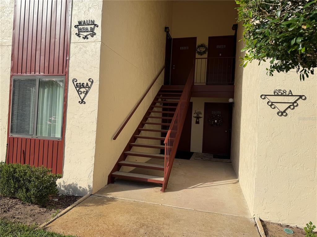 An exterior view of a two-story apartment building with a central staircase and brown doors — 656 MIDWAY DRIVE UNIT A, OCALA, FL
