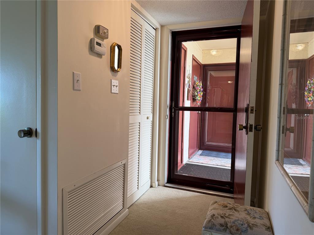 An entryway features a louvered closet door, a wall-mounted thermostat, and a glass storm door — 656 MIDWAY DRIVE UNIT A, OCALA, FL