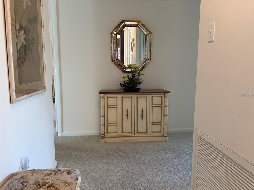 A hallway features a wooden cabinet, an octagonal mirror, and a framed floral print — 656 MIDWAY DRIVE UNIT A, OCALA, FL