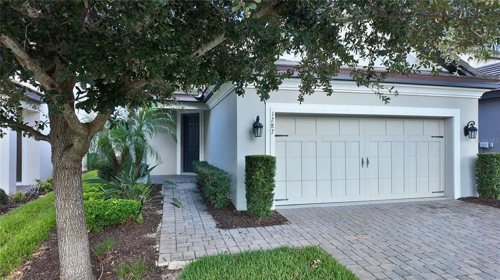 A single-story house exterior features a paved driveway, a two-car garage, and a landscaped walkway — 1287 VERDANT GLADE PLACE, WINTER PARK, FL