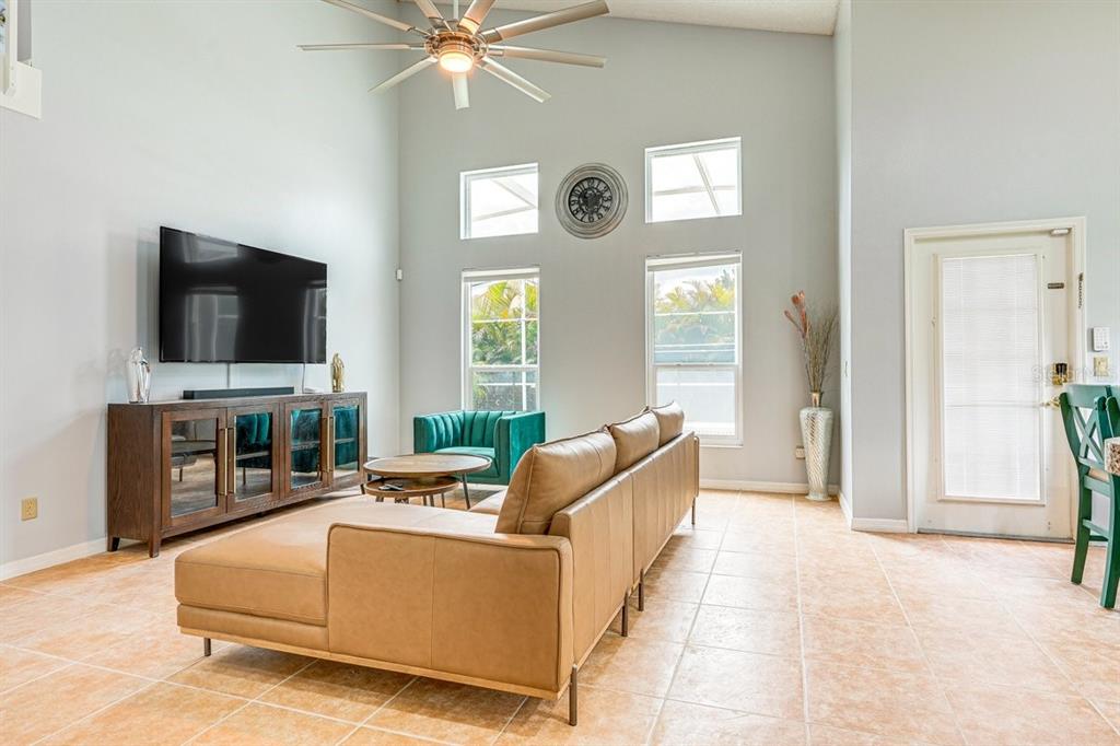 A living room features a tan leather sectional, a television console, and a ceiling fan — 418 RIGGS CIRCLE, DAVENPORT, FL