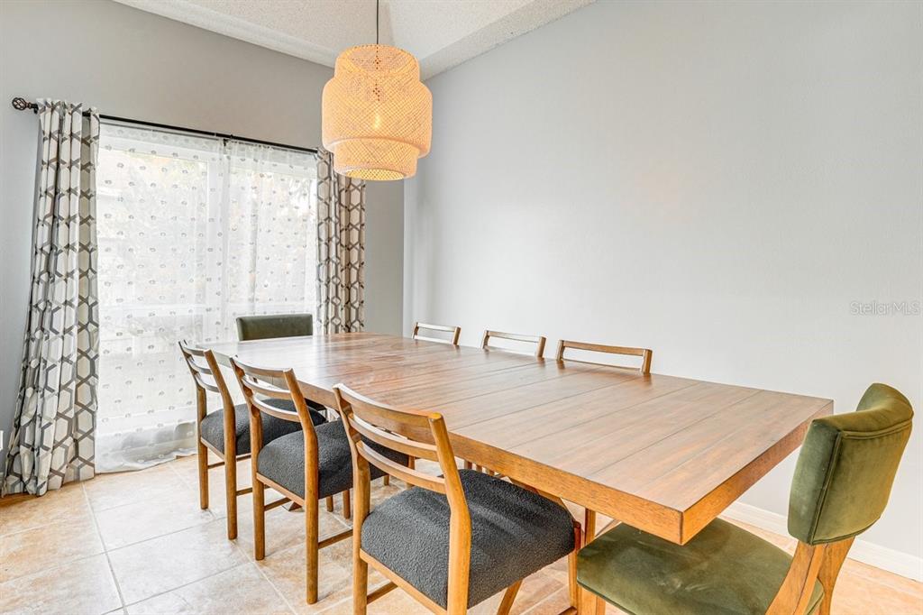 A dining room features a long wooden table, six chairs, and a woven pendant light — 418 RIGGS CIRCLE, DAVENPORT, FL
