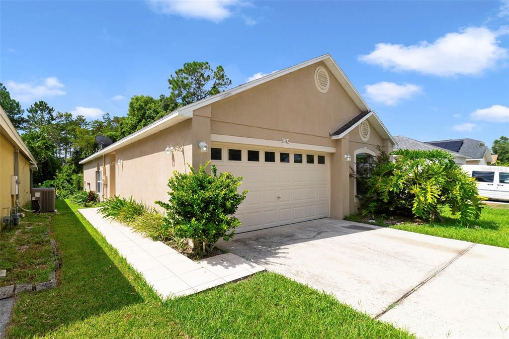 A tan, single-story house with a two-car garage and a concrete driveway — 13142 ODYSSEY LAKE WAY, ORLANDO, FL