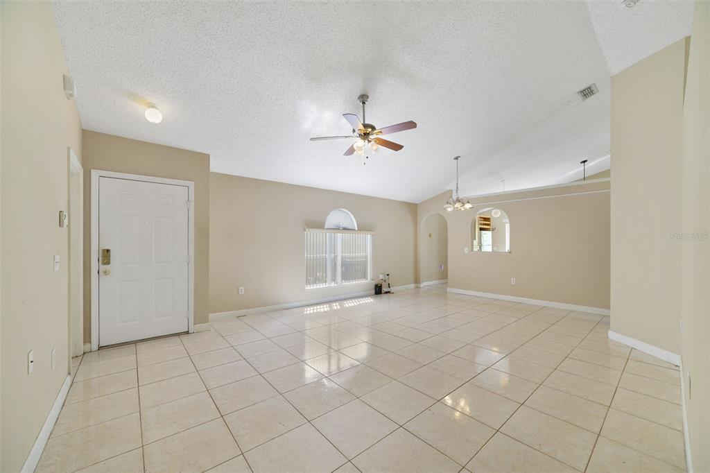 An open living area with beige walls, white tile flooring, and a ceiling fan — 13142 ODYSSEY LAKE WAY, ORLANDO, FL