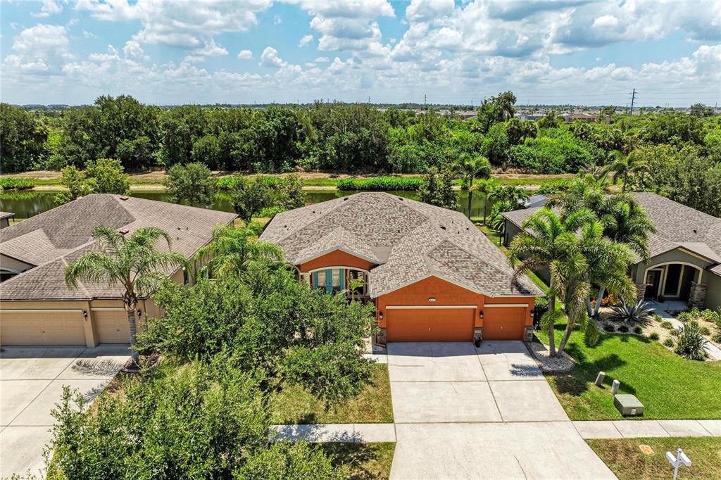 An aerial view shows a suburban house with an orange exterior and a three-car garage — 316 STAR SHELL DRIVE, APOLLO BEACH, FL