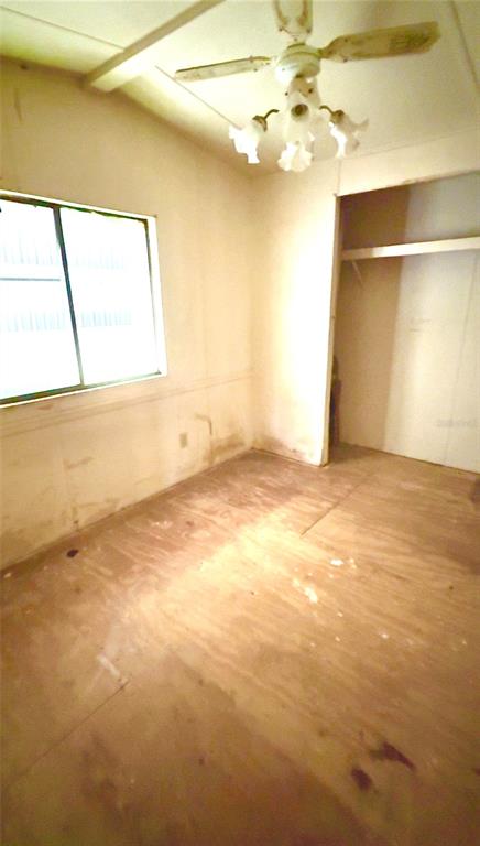 An empty bedroom features unfinished plywood flooring, plain walls, a ceiling fan, and a closet — 19399 FORT DADE AVENUE, BROOKSVILLE, FL