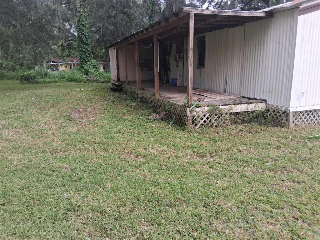 An exterior view of a mobile home featuring a covered wooden porch and lattice skirting — 19399 FORT DADE AVENUE, BROOKSVILLE, FL