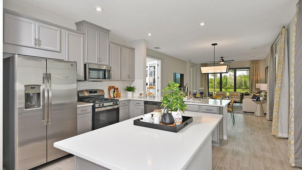 A kitchen with gray cabinets, stainless steel appliances, and a white island with a tray — 13507 ROWHOUSE COURT, PARRISH, FL