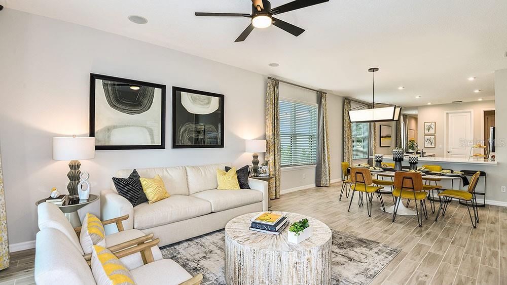 A bright open-concept living and dining area features light wood-look tile flooring and modern decor — 13507 ROWHOUSE COURT, PARRISH, FL