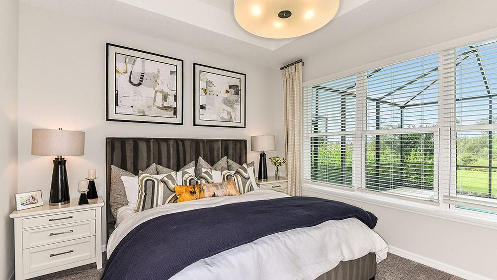 A bedroom features a dark upholstered headboard, two framed abstract prints, and large windows — 13507 ROWHOUSE COURT, PARRISH, FL