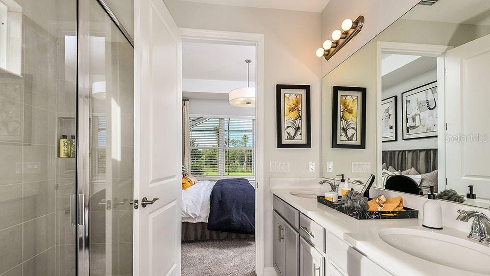 A bathroom with a glass-enclosed shower, gray vanity, and a view into a bedroom — 13507 ROWHOUSE COURT, PARRISH, FL