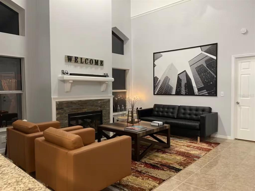 A living room features a stone fireplace, two tan armchairs, a black sofa, and artwork — 102 W FREDERICK AVENUE, LAKE MARY, FL