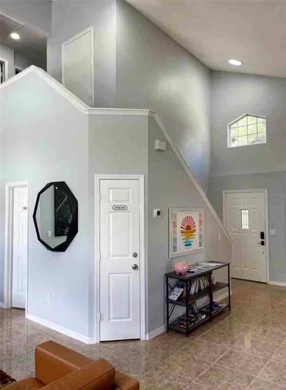 An entryway with light gray walls, tile flooring, a storage closet, and a front door — 102 W FREDERICK AVENUE, LAKE MARY, FL