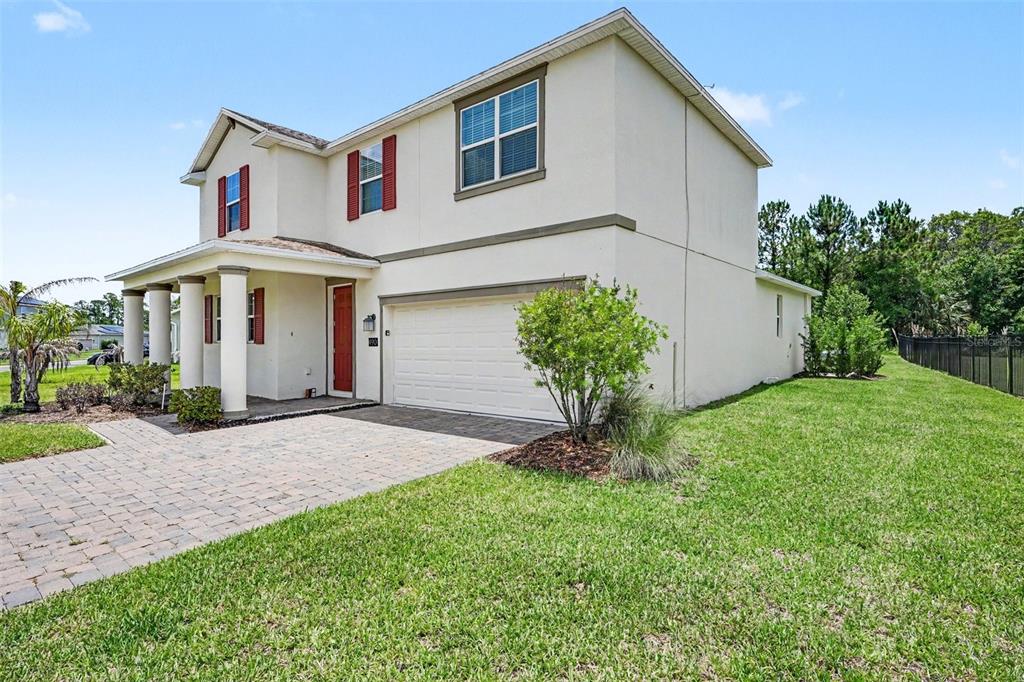 A two-story house with a beige stucco exterior, red shutters, and a front porch — 490 BRUNSWICK DRIVE, DAVENPORT, FL