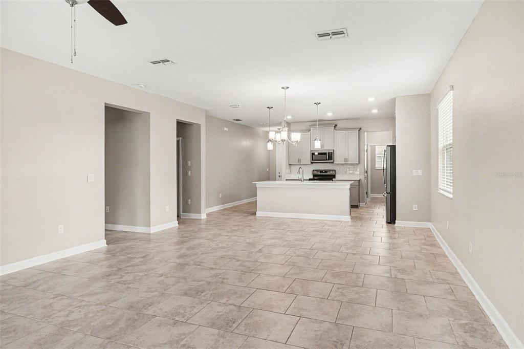 An empty bedroom features beige walls, gray carpeting, a ceiling fan, and two windows — 490 BRUNSWICK DRIVE, DAVENPORT, FL