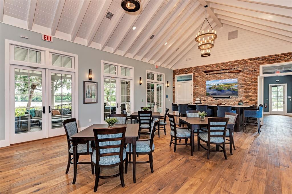 A spacious room features vaulted ceilings, a brick accent wall, and multiple dining tables — 11815 RIVER SHORES TRAIL, PARRISH, FL