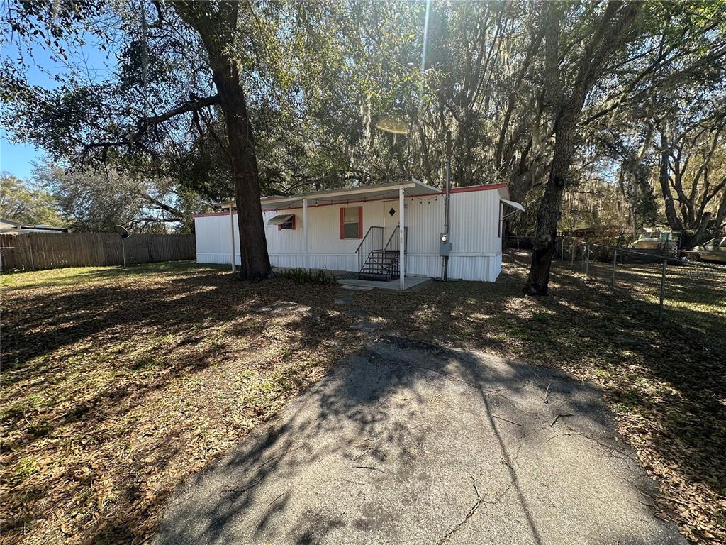 A white mobile home sits on a lot with mature trees and a paved driveway — 9150 SE 142ND PLACE, SUMMERFIELD, FL