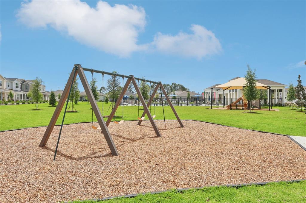 A playground with a swing set and a covered play area on a grassy lawn — 1819 LATTICE WAY, ST CLOUD, FL