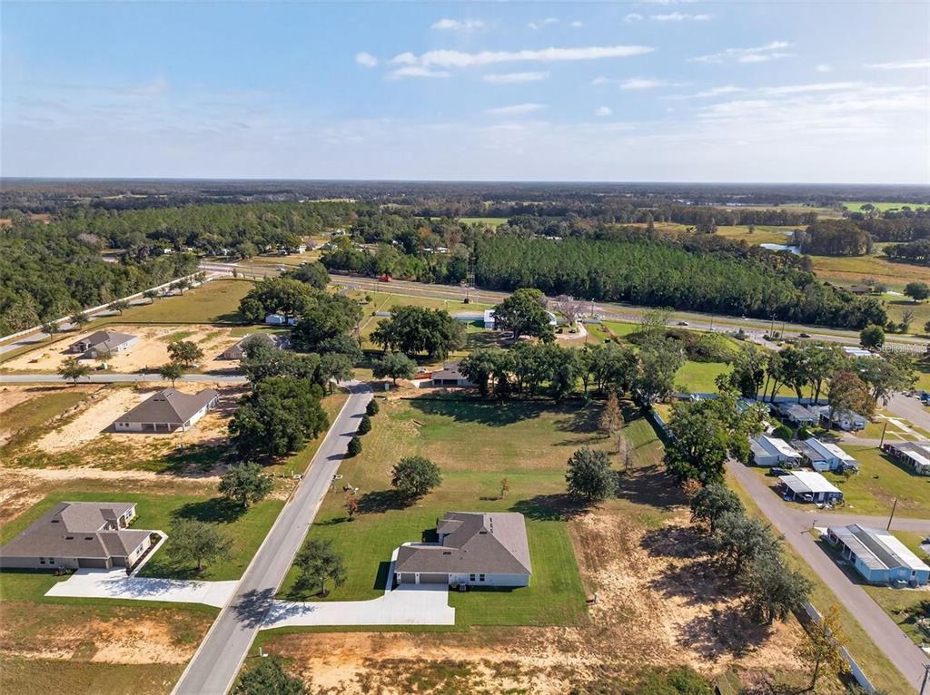 An aerial view shows several suburban houses situated on large, grassy lots near a road — 36893 HIDDEN VIEW CIRCLE, DADE CITY, FL