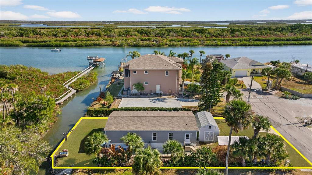 An aerial view shows a house with a shed and yard outlined in yellow near water — 185 COLEMAN STREET, EDGEWATER, FL