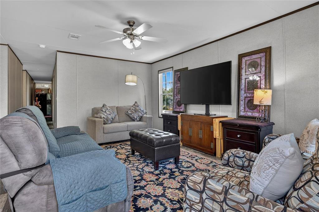 A living room features a patterned area rug, a television on a cabinet, and seating — 185 COLEMAN STREET, EDGEWATER, FL