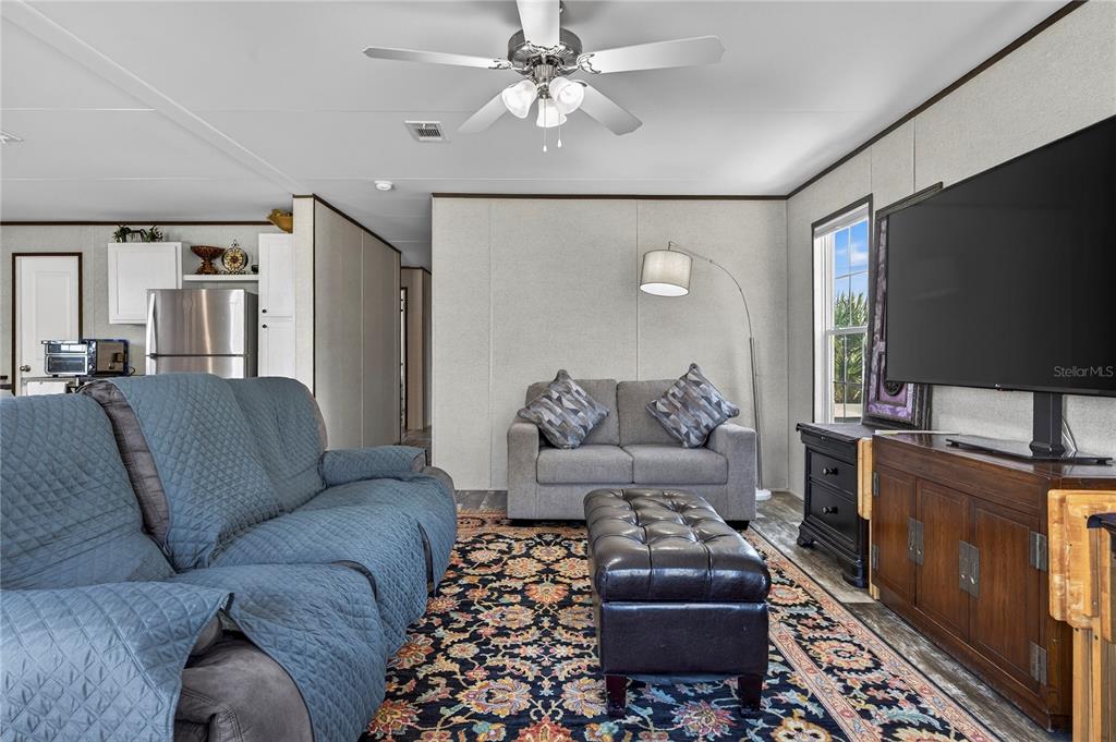 A living room features a blue sofa, a grey loveseat, a leather ottoman, and a television — 185 COLEMAN STREET, EDGEWATER, FL