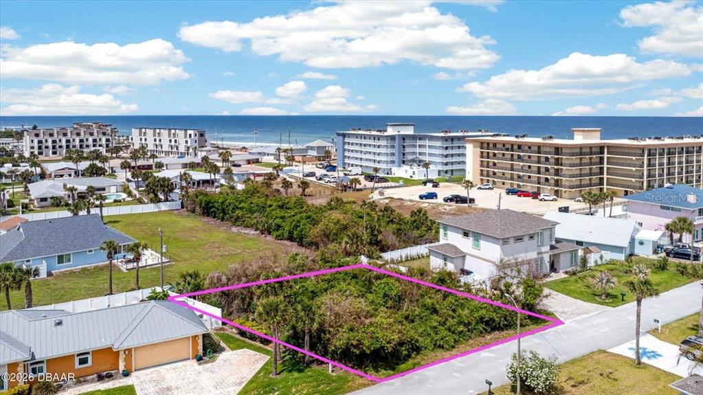 An aerial view shows a vacant, rectangular lot outlined in pink near the ocean — 28 OCEAN BREEZE CIRCLE, ORMOND BEACH, FL