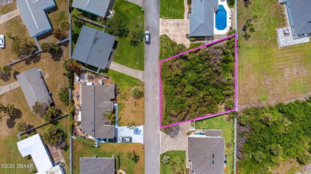 An aerial view shows a vacant, rectangular lot outlined in pink along a residential street — 28 OCEAN BREEZE CIRCLE, ORMOND BEACH, FL
