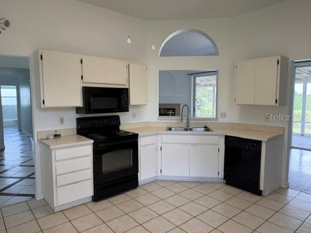 A kitchen features white cabinets, black appliances, a corner sink, and light-colored tile flooring — 4633 HAZELGROVE DRIVE, ORLANDO, FL