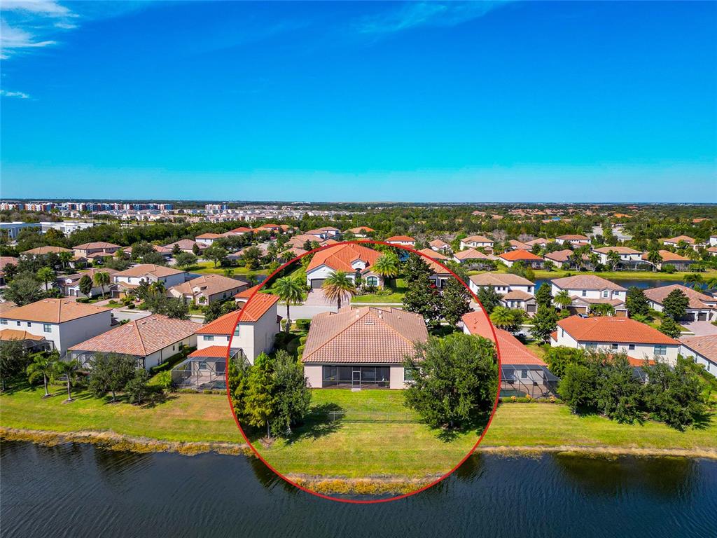 An aerial view of a suburban house with a screened lanai overlooking a lake — 13026 RAMBLEWOOD TRAIL, BRADENTON, FL