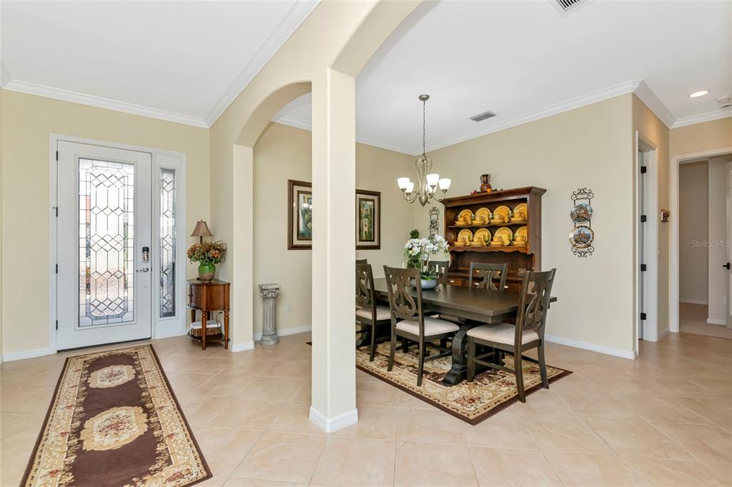 A dining area with a wooden table and hutch sits adjacent to an entryway foyer — 13026 RAMBLEWOOD TRAIL, BRADENTON, FL