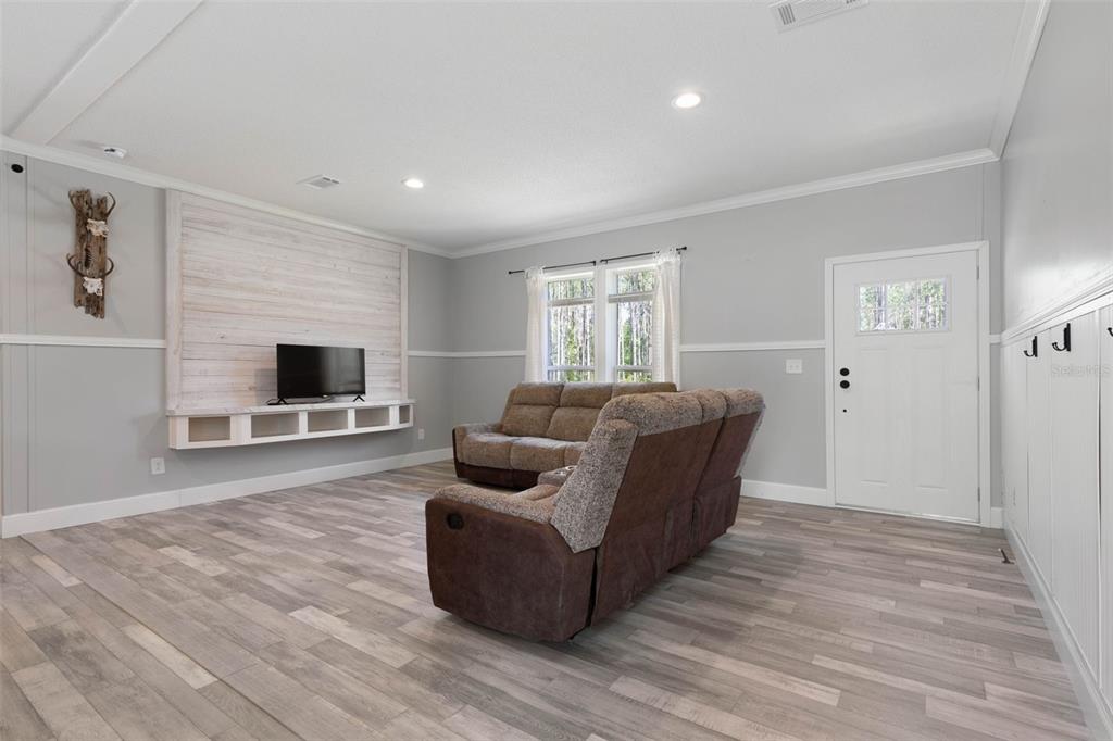 A living room features light gray walls, wood-look flooring, a shiplap accent wall, and a recliner — 15539 COUNTY RD 305, BUNNELL, FL