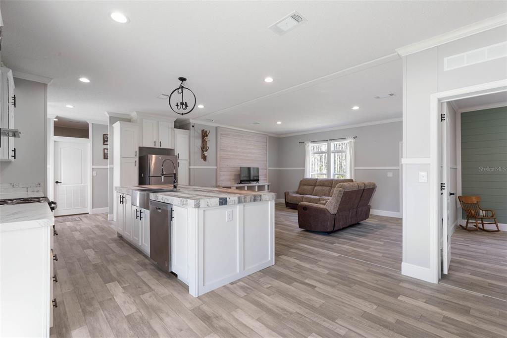 A kitchen with a white island and stainless steel appliances opens into a living area — 15539 COUNTY RD 305, BUNNELL, FL