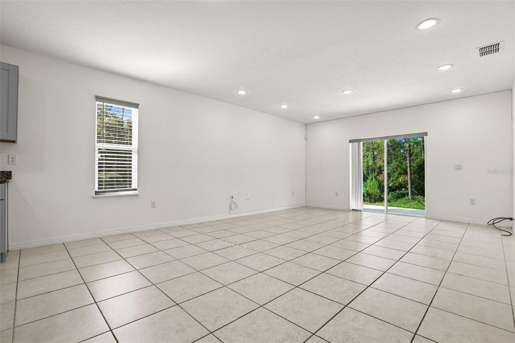 An empty room with white walls, tiled floors, recessed lighting, and a sliding glass door — 2860 SURF DRIVE, DELTONA, FL
