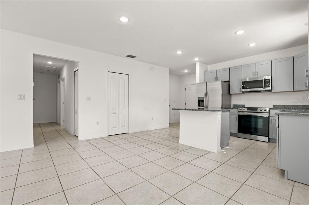A kitchen with light gray cabinets, stainless steel appliances, and a central island on tile flooring — 2860 SURF DRIVE, DELTONA, FL