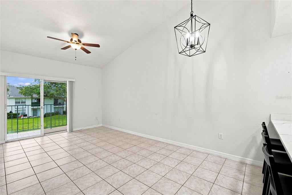 A dining area with tile flooring, a geometric chandelier, a ceiling fan, and sliding glass doors — 5005 BORDEAUX VILLAGE PLACE UNIT 202, TAMPA, FL