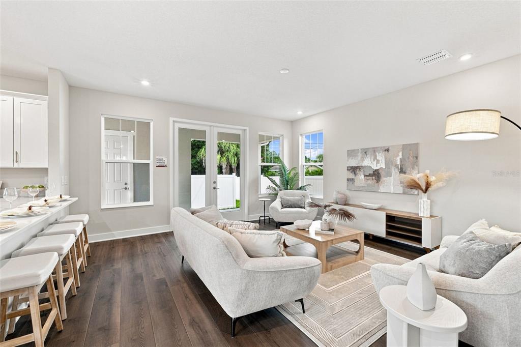 A bright living room features wood floors, a white sofa, and a kitchen breakfast bar — 5633 DARTMOUTH AVENUE N, ST PETERSBURG, FL