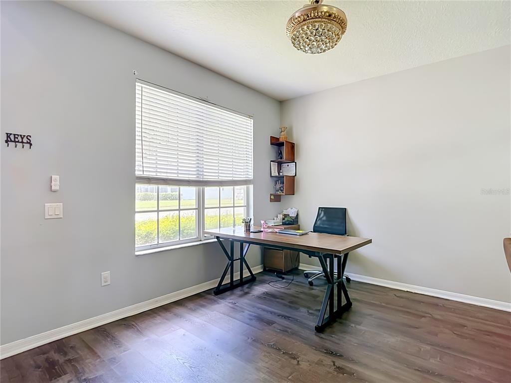 A home office features a wooden desk, a window with blinds, and wood-look flooring — 4129 TARKINGTON DRIVE, LAND O LAKES, FL