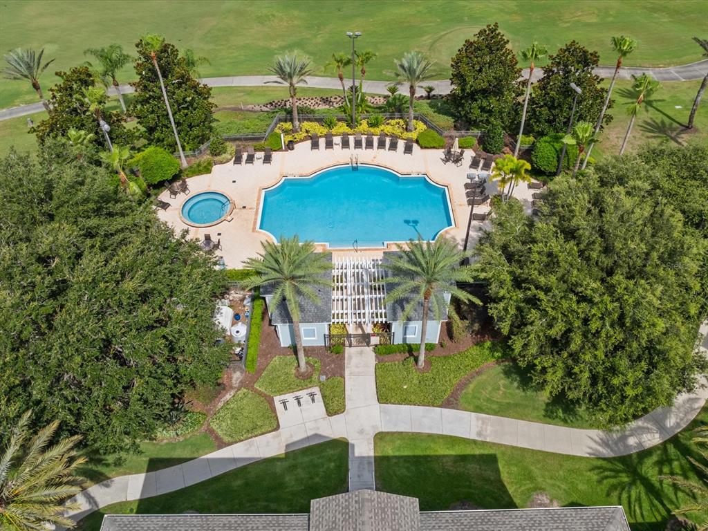 An aerial view shows a swimming pool and hot tub surrounded by trees and landscaping — 7615 HERITAGE CROSSING WAY UNIT 201, REUNION, FL