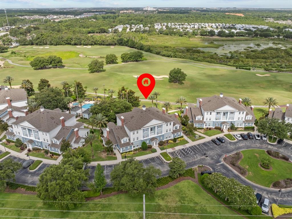 An aerial view shows a multi-story residential building complex situated next to a golf course — 7615 HERITAGE CROSSING WAY UNIT 201, REUNION, FL