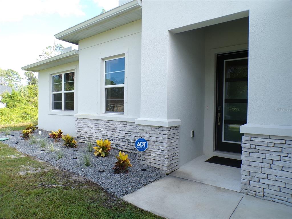 A modern house exterior features white stucco walls, stone veneer accents, and a front entryway — 2871 ARMENIA ROAD, NORTH PORT, FL