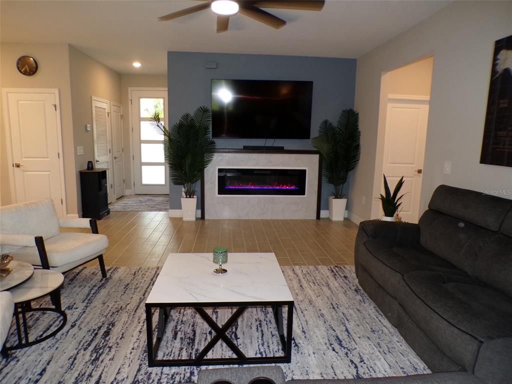 A living room features a blue accent wall with a fireplace, television, and tile flooring — 2871 ARMENIA ROAD, NORTH PORT, FL