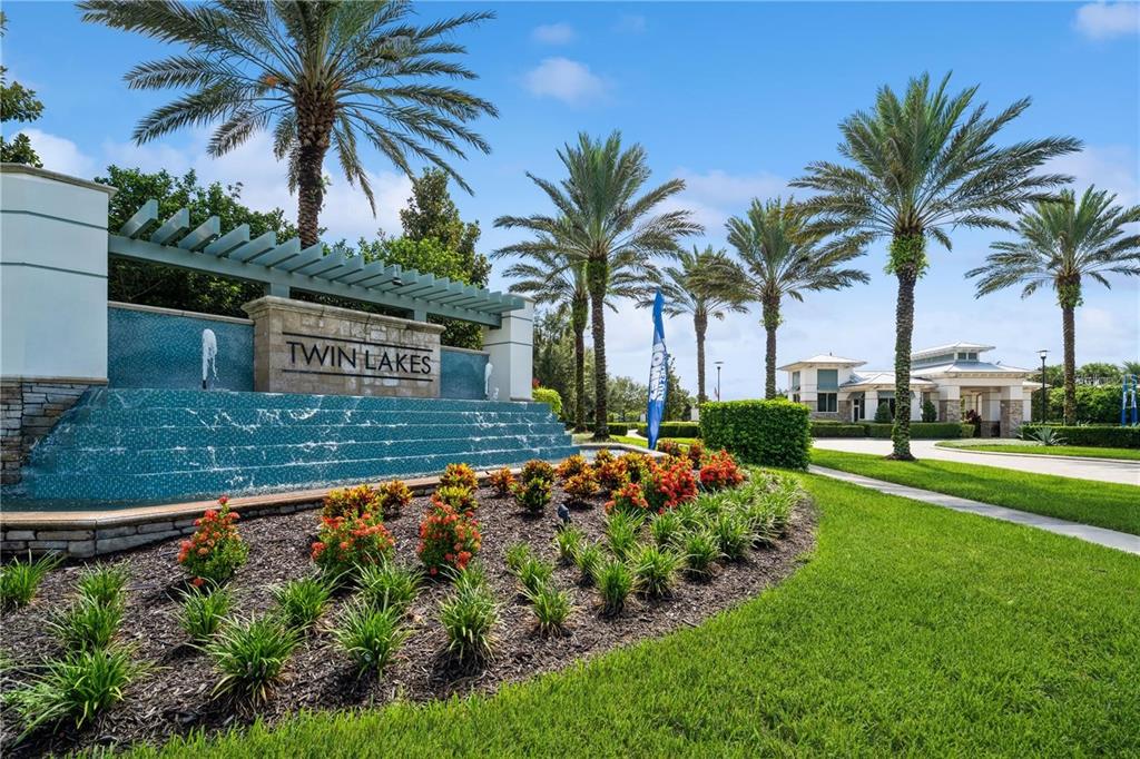 A stone monument sign for Twin Lakes stands before a tiered water feature and landscaping — 5019 DANCY LANE, ST CLOUD, FL