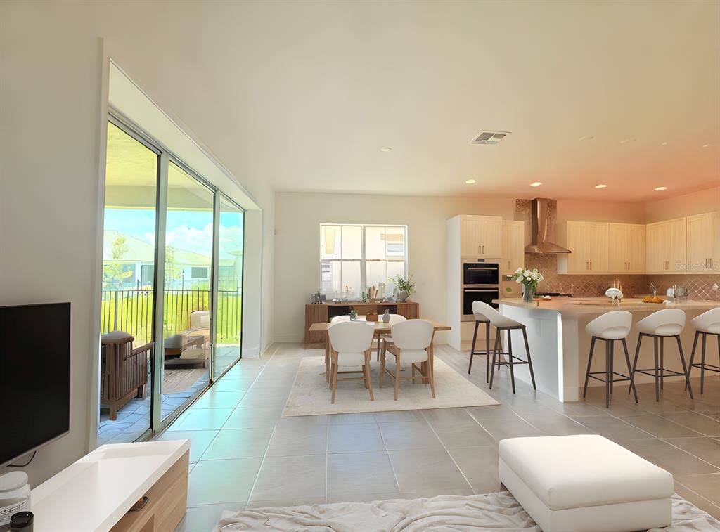 An open-concept kitchen and dining area features tile flooring, a large island, and sliding doors — 5019 DANCY LANE, ST CLOUD, FL