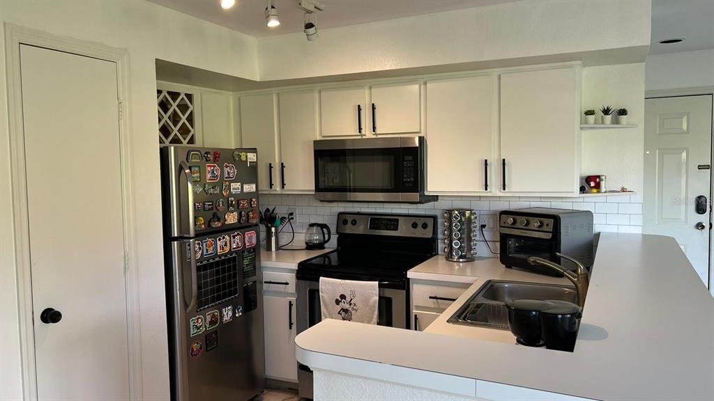 A dining area with a glass table and a kitchen with a breakfast bar — 7310 WESTPOINTE BOULEVARD UNIT 623, ORLANDO, FL